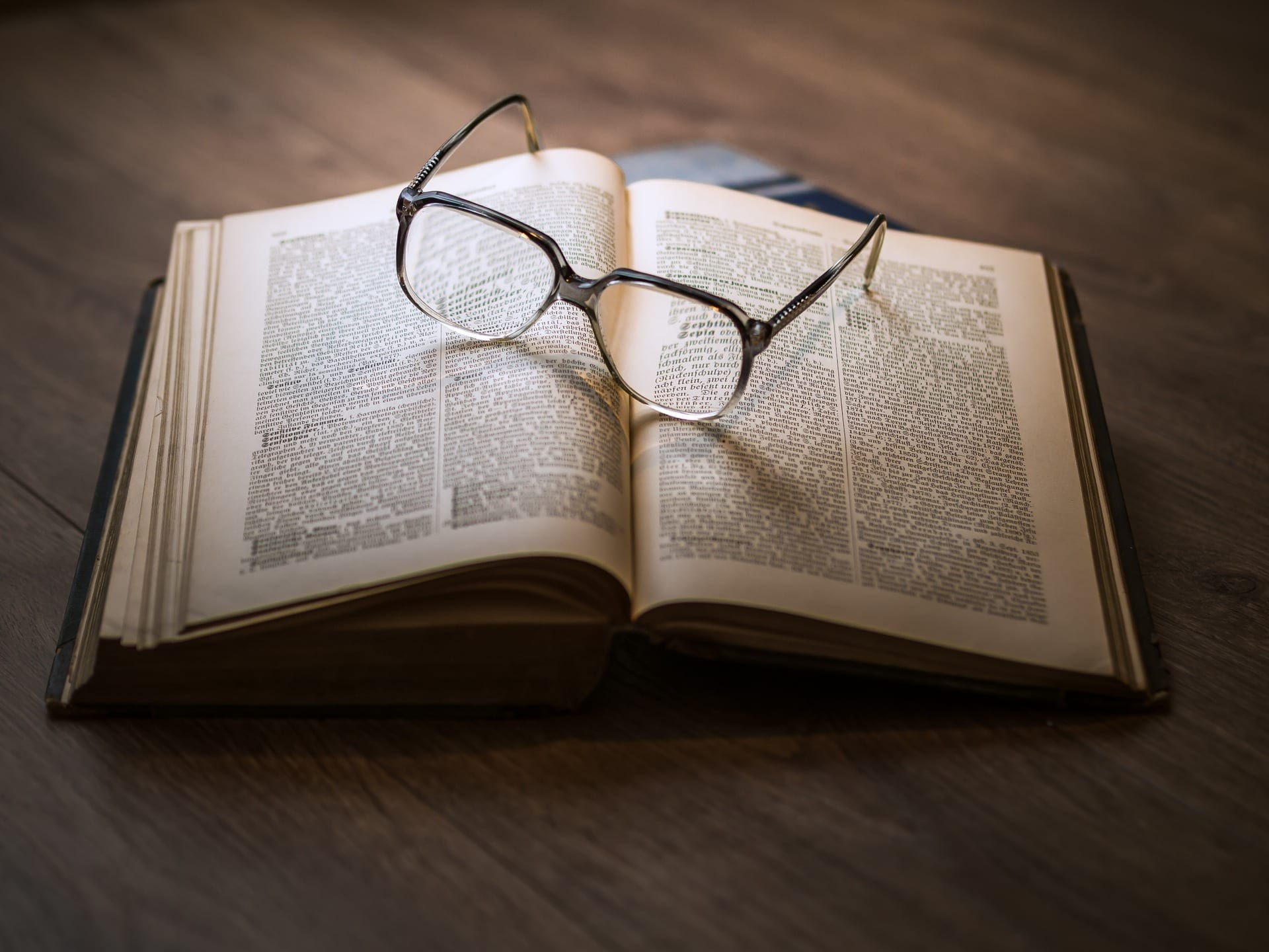 A picture of an open text based book with glasses on top.